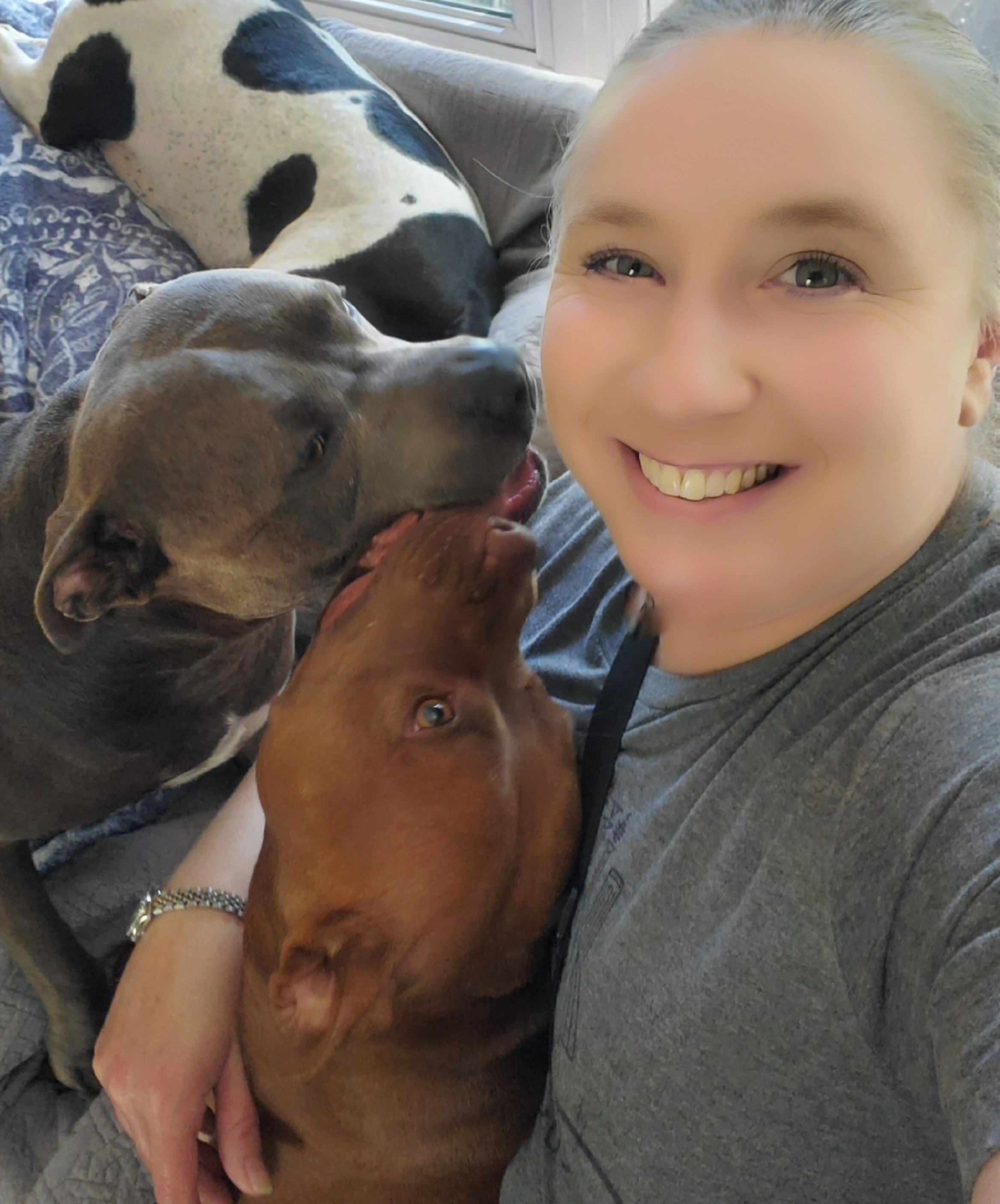 Kelly smiling with two Pit Bulls — all breeds welcome at KJT Gentle Dog Training